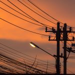 Redes Elétricas Convencionais: Estrutura, Componentes e Impacto no Dia a Dia Lamp post and telephone line with a background sunset on the street