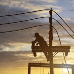 Electricians work on high voltage towers to install new wires and equipment.